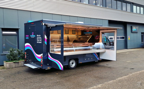 Zijaanzicht van een verkoopwagen voor vis met geopende luifel en zijborden