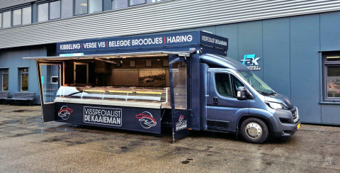Zijaanzicht van een verkoopwagen voor vis met geopende luifel en zijborden