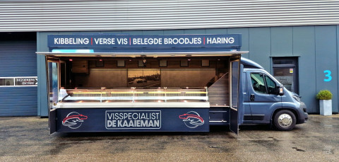 Zijaanzicht van een verkoopwagen voor vis met geopende luifel en zijborden