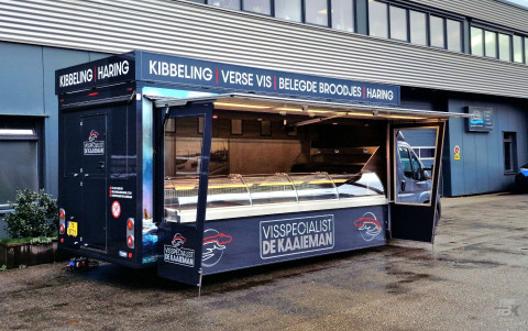 Zijaanzicht van een verkoopwagen voor vis met geopende luifel en zijborden