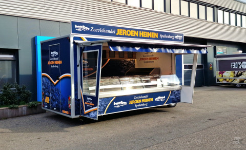 Zijaanzicht van een aanhangwagen voor vis met geopende luifel en zijborden