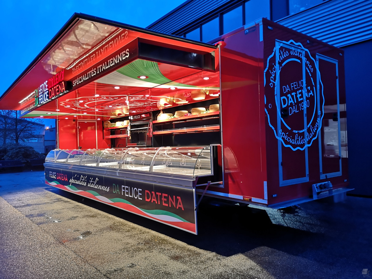 Zijaanzicht van een verkoopwagen oplegger voor Italiaanse delicatessen met geopende luifel en verlichting