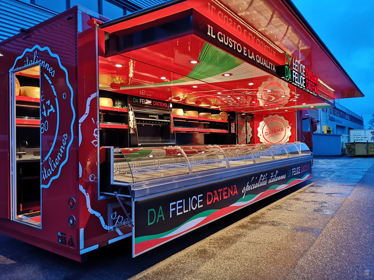 Zijaanzicht van een verkoopwagen oplegger voor Italiaanse delicatessen met geopende luifel en verlichting