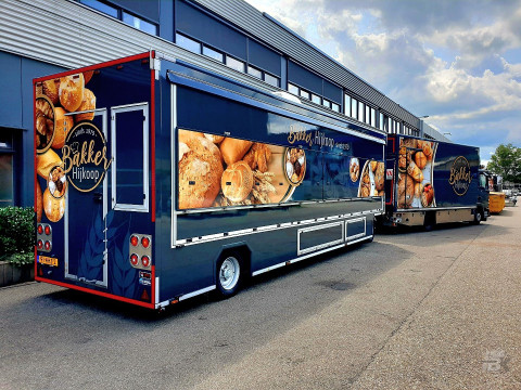 Zijaanzicht van twee verkoopwagens voor brood en banket met gesloten luifels