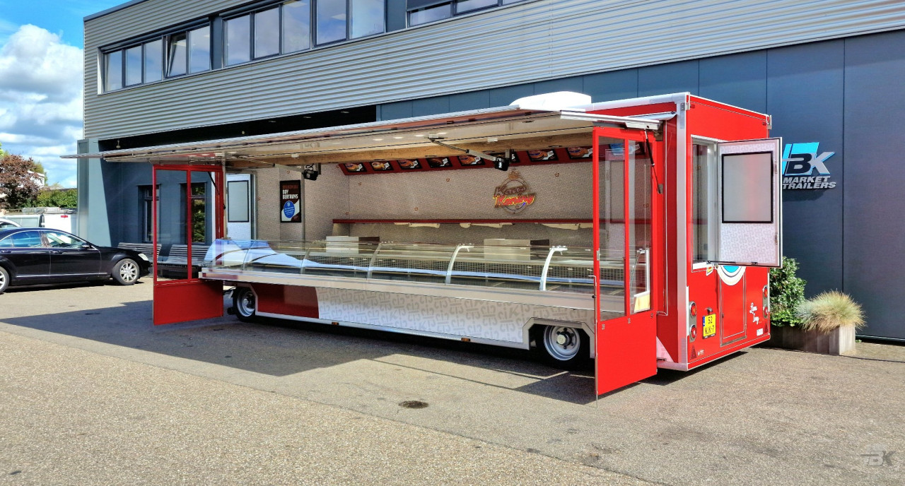 Zijaanzicht van een aanhangwagen voor kaas met geopende luifel en zijborden