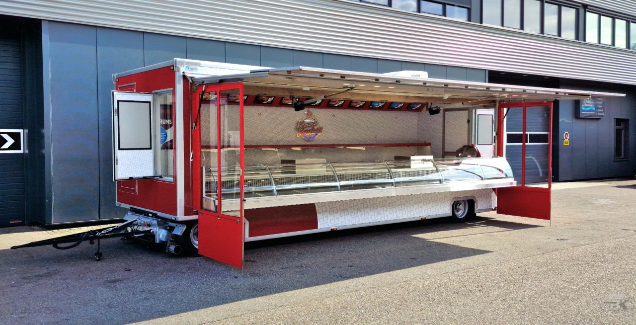 Zijaanzicht van een aanhangwagen voor kaas met geopende luifel en zijborden