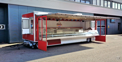 Zijaanzicht van een aanhangwagen voor kaas met geopende luifel en zijborden