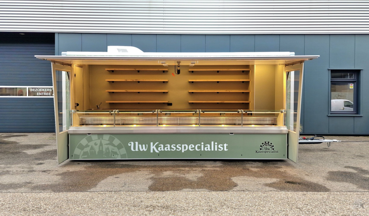 Zijaanzicht van een aanhangwagen voor kaas met geopende luifel en zijborden