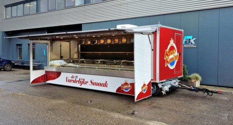Zijaanzicht van een aanhangwagen voor kaas met geopende luifel en zijborden