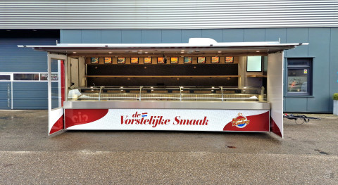 Zijaanzicht van een aanhangwagen voor kaas met geopende luifel en zijborden