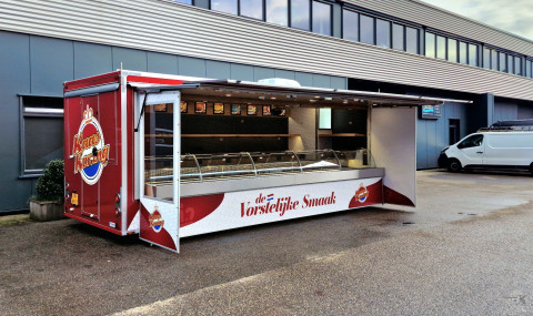 Zijaanzicht van een aanhangwagen voor kaas met geopende luifel en zijborden