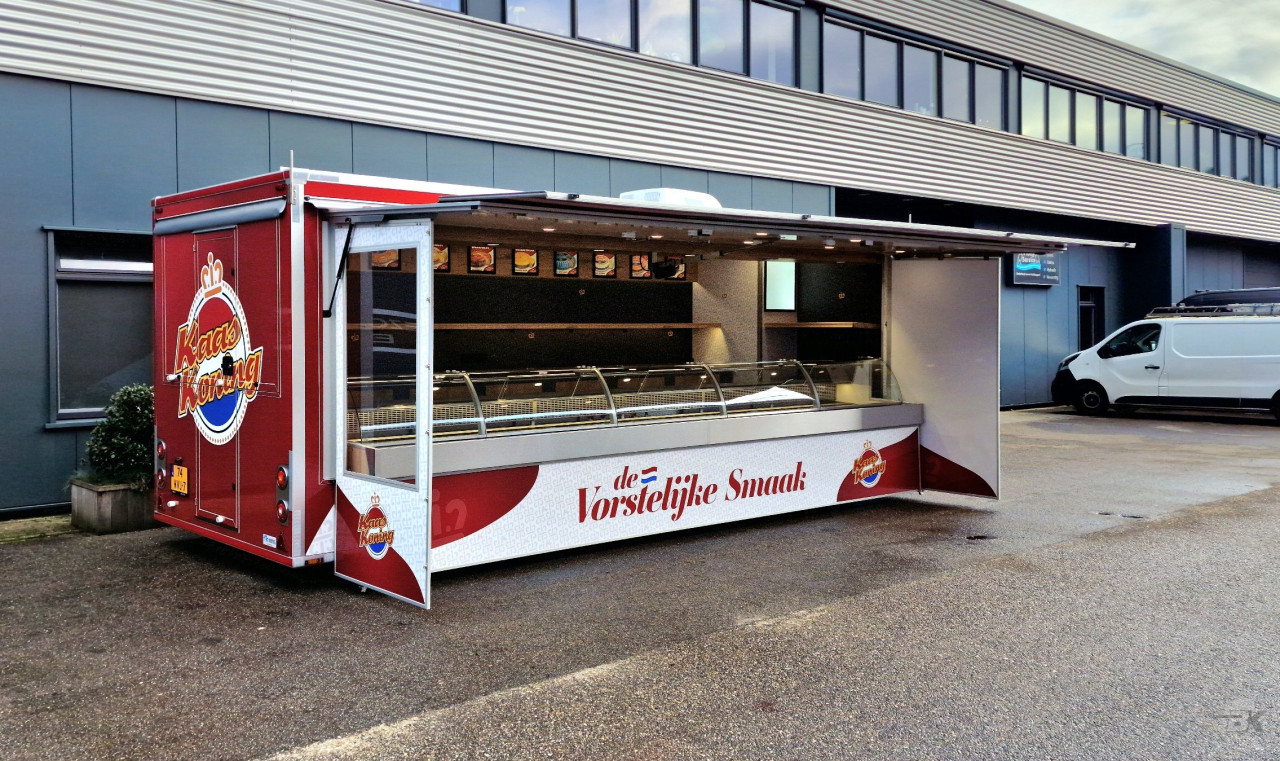 Zijaanzicht van een aanhangwagen voor kaas met geopende luifel en zijborden