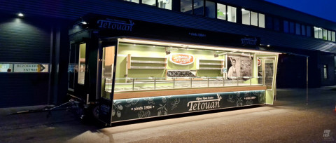 Zijaanzicht van een aanhangwagen voor olijven, tapas en noten met geopende luifel en verlichting