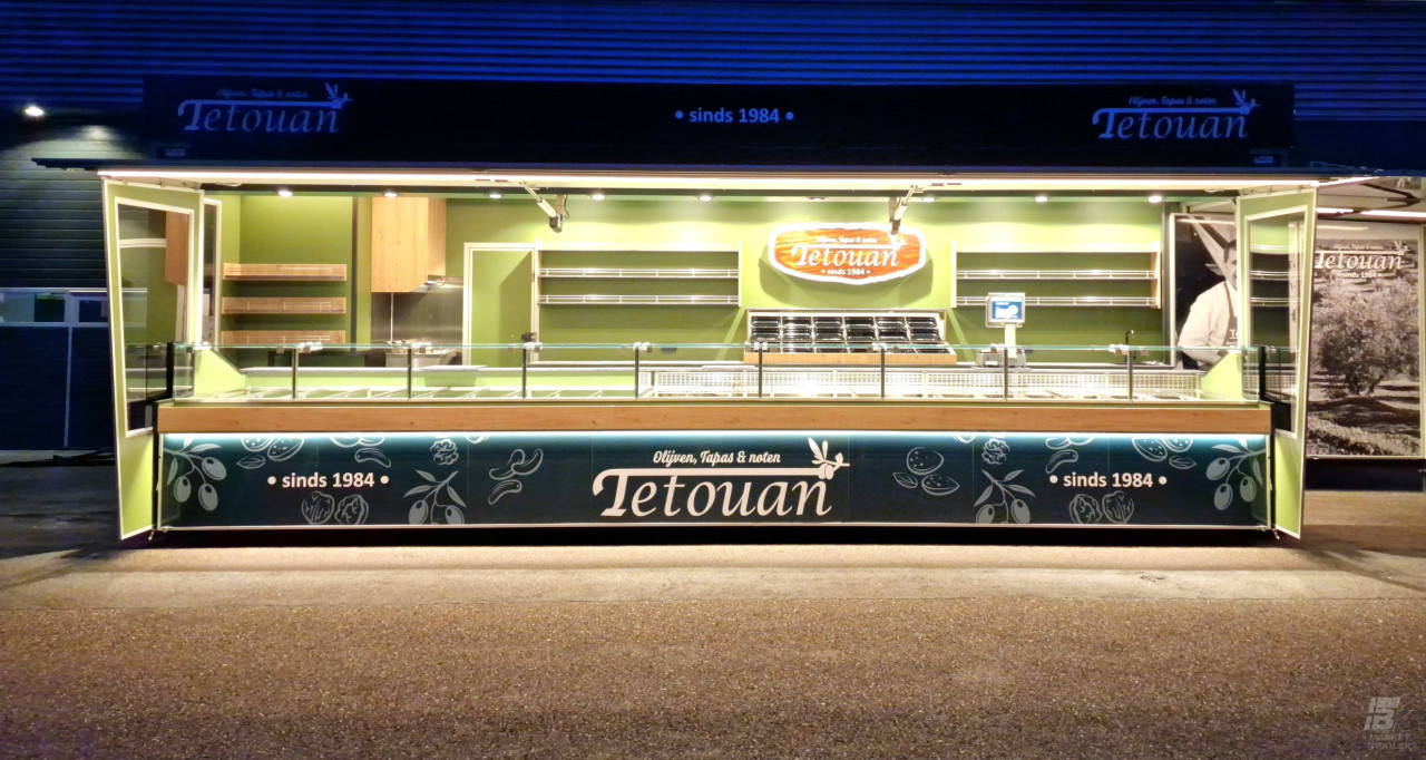 Zijaanzicht van een aanhangwagen voor olijven, tapas en noten met geopende luifel en verlichting