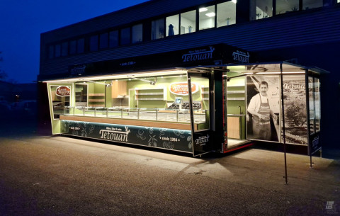 Zijaanzicht van een aanhangwagen voor olijven, tapas en noten met geopende luifel en verlichting