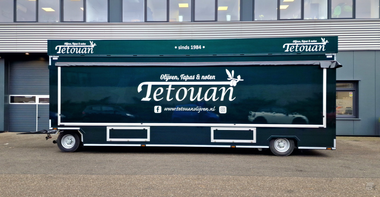 Zijaanzicht van een aanhangwagen voor olijven, tapas en noten met gesloten luifel