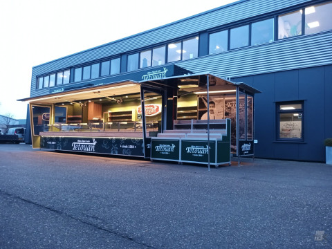 Zijaanzicht van een aanhangwagen voor olijven, tapas en noten met geopende luifel en verlichting