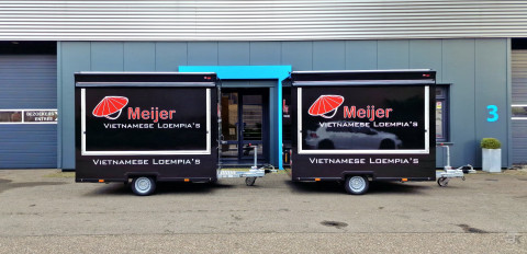 Zijaanzicht van twee kleine aanhangwagens voor loempia's met gesloten luifels