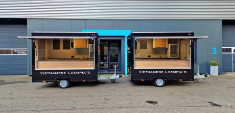 Zijaanzicht van twee kleine aanhangwagens voor loempia's met geopende luifels