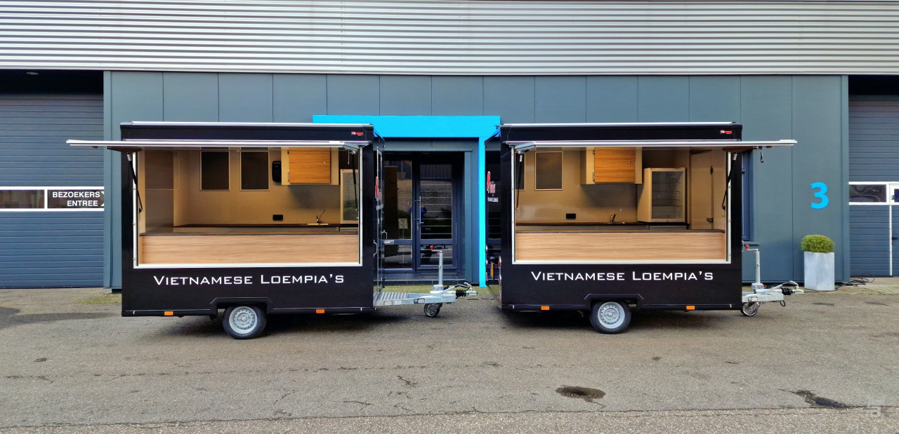 Zijaanzicht van twee kleine aanhangwagens voor loempia's met geopende luifels