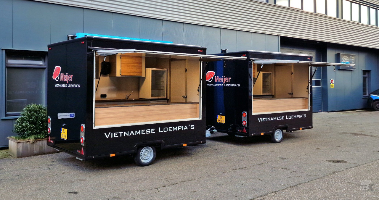 Zijaanzicht van twee kleine aanhangwagens voor loempia's met geopende luifels