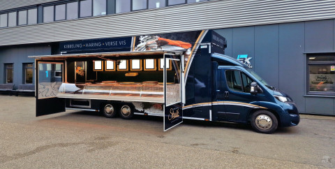 Zijaanzicht van een verkoopwagen voor vis met geopende luifel en zijborden