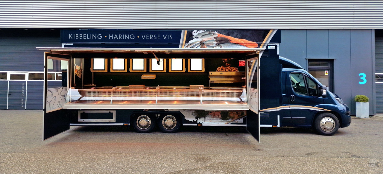 Zijaanzicht van een verkoopwagen voor vis met geopende luifel en zijborden
