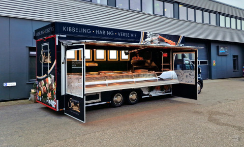 Zijaanzicht van een verkoopwagen voor vis met geopende luifel en zijborden