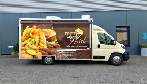 Zijaanzicht van een verkoopwagen voor patat met gesloten luifel