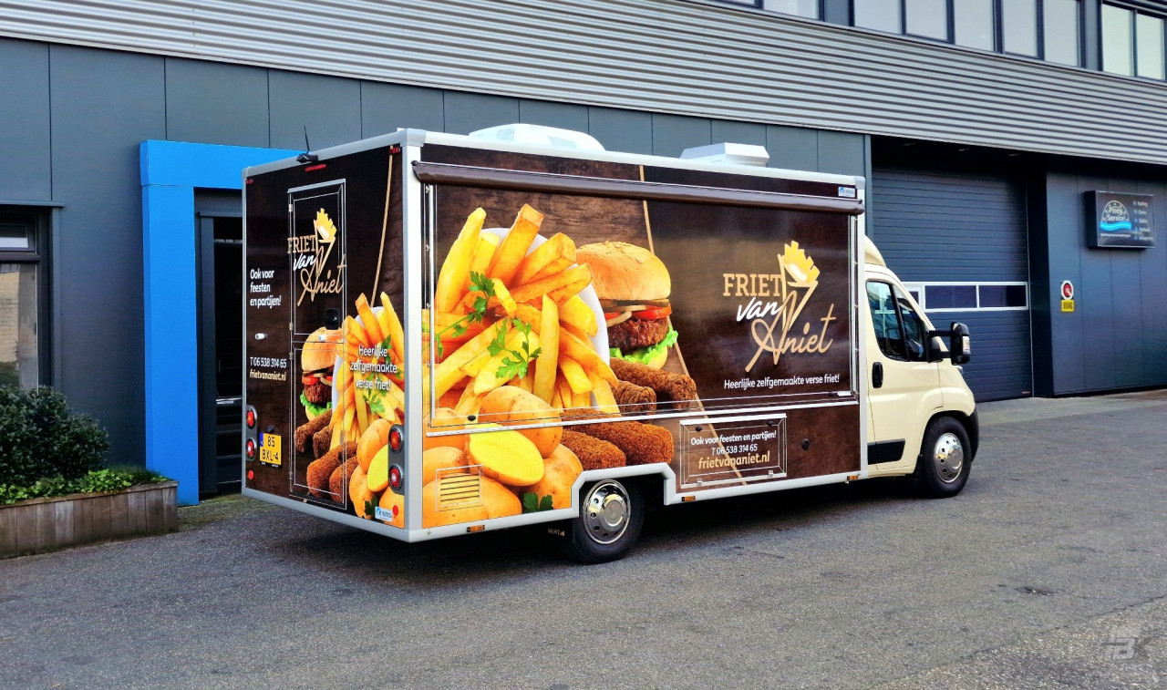 Zijaanzicht van een verkoopwagen voor patat met gesloten luifel