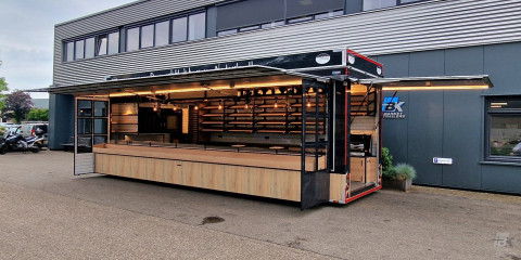 Zijaanzicht van een aanhangwagen voor brood en banket met geopende luifel en zijborden