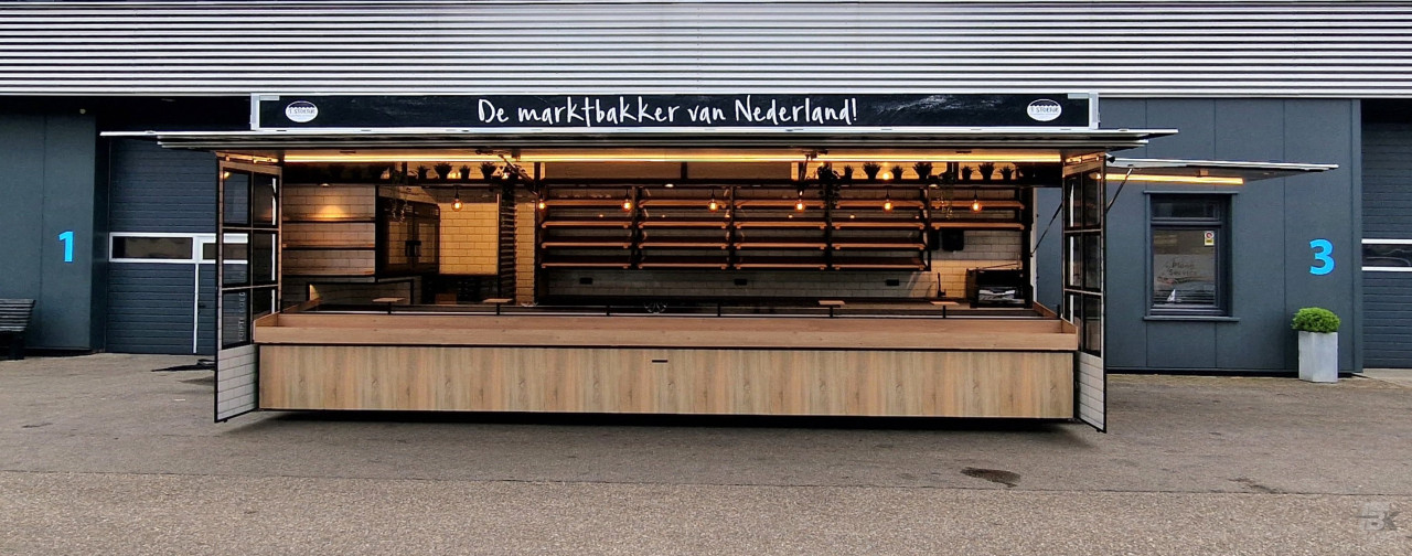 Zijaanzicht van een aanhangwagen voor brood en banket met geopende luifel en zijborden