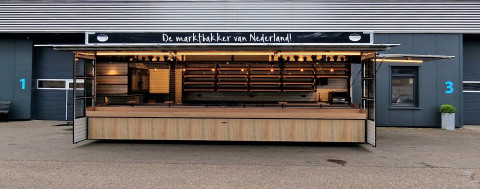 Zijaanzicht van een aanhangwagen voor brood en banket met geopende luifel en zijborden