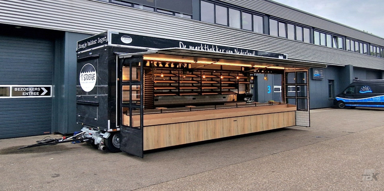 Zijaanzicht van een aanhangwagen voor brood en banket met geopende luifel en zijborden
