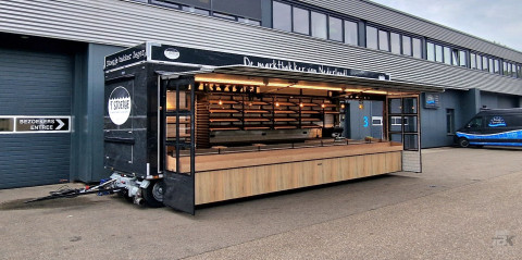 Zijaanzicht van een aanhangwagen voor brood en banket met geopende luifel en zijborden