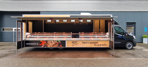 Zijaanzicht van een verkoopwagen voor vlees met geopende luifel en zijborden