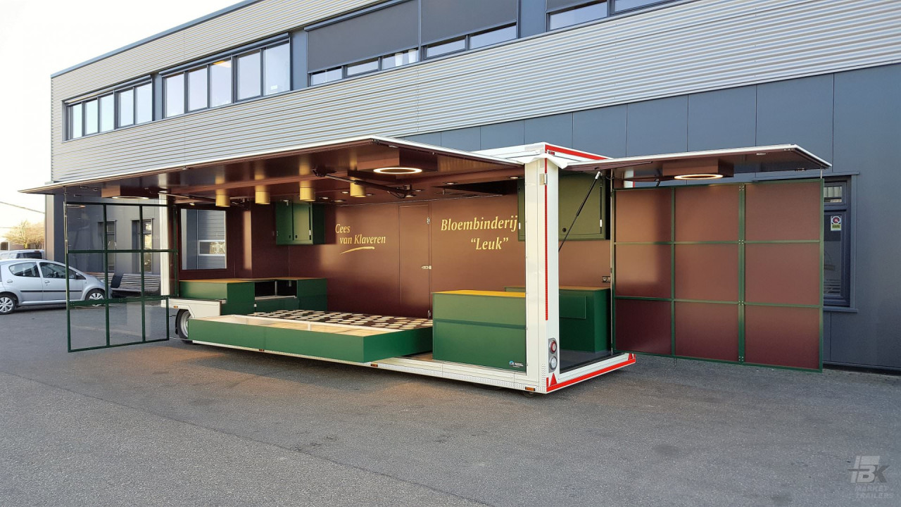 Zijaanzicht van een aanhangwagen voor bloemen met geopende luifel en zijbord