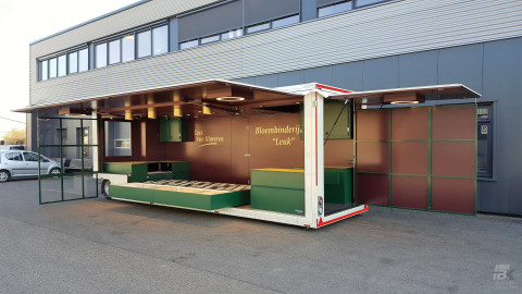 Zijaanzicht van een aanhangwagen voor bloemen met geopende luifel en zijbord
