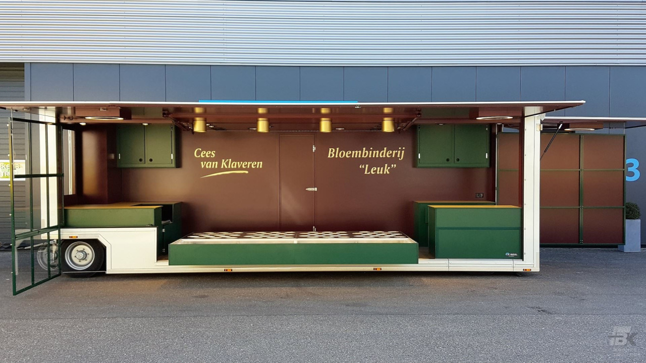Zijaanzicht van een aanhangwagen voor bloemen met geopende luifel en zijbord