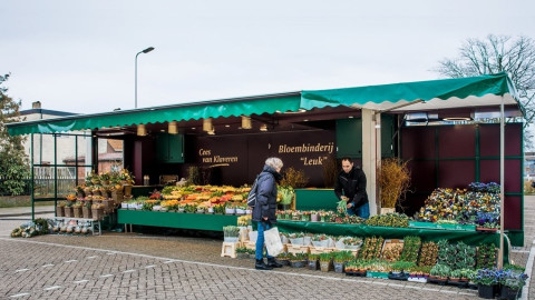 Volledig uitgestalde aanhangwagen voor bloemen, met een bezoeker en verkoper
