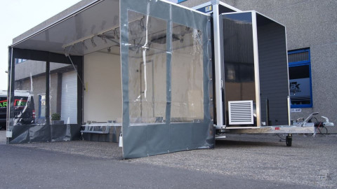 Zijaanzicht van een aanhangwagen voor damesmode met geopende luifel en zijborden