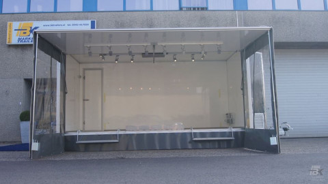 Zijaanzicht van een aanhangwagen voor damesmode met geopende luifel en zijborden