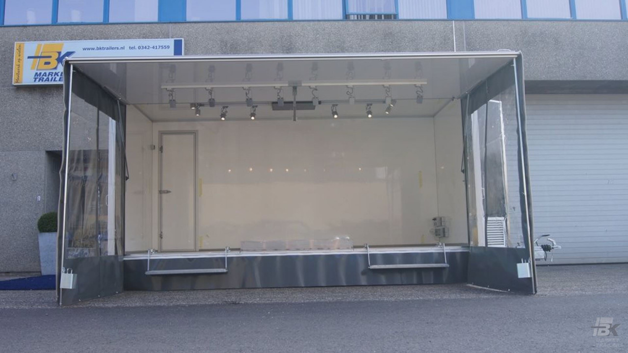 Zijaanzicht van een aanhangwagen voor damesmode met geopende luifel en zijborden