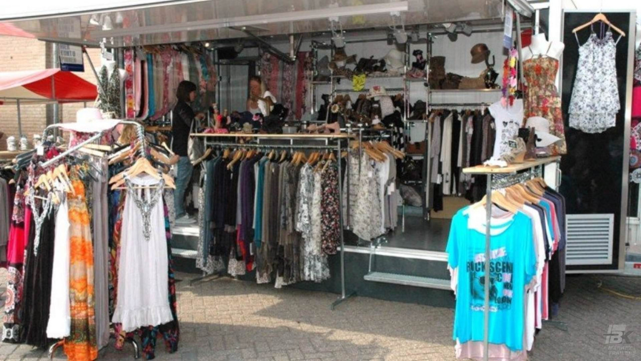 Volledig uitgestalde aanhangwagen voor damesmode, met een bezoeker en verkoper
