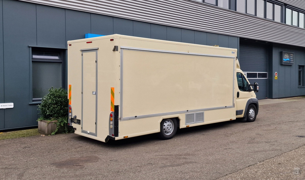 Zijaanzicht van een verkoopwagen voor diverse branches met gesloten luifel