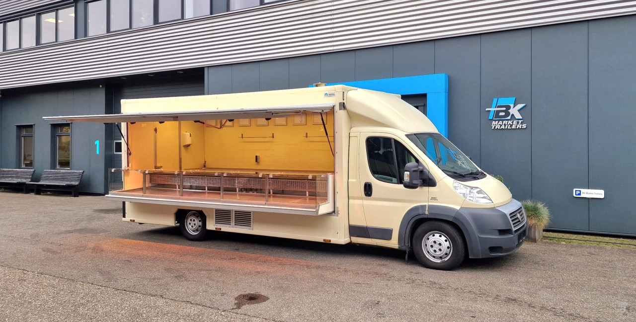 Zijaanzicht van een verkoopwagen voor diverse branches met geopende luifel