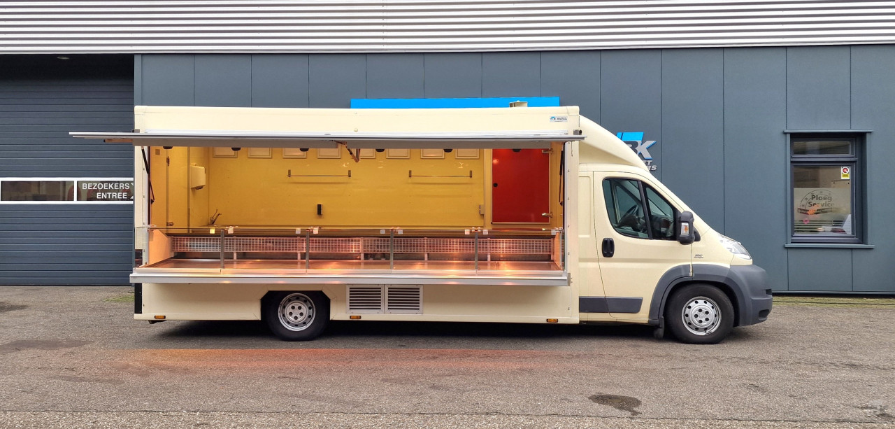 Zijaanzicht van een verkoopwagen voor diverse branches met geopende luifel