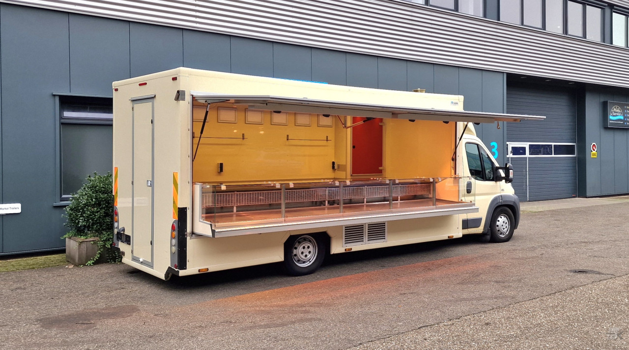 Zijaanzicht van een verkoopwagen voor diverse branches met geopende luifel