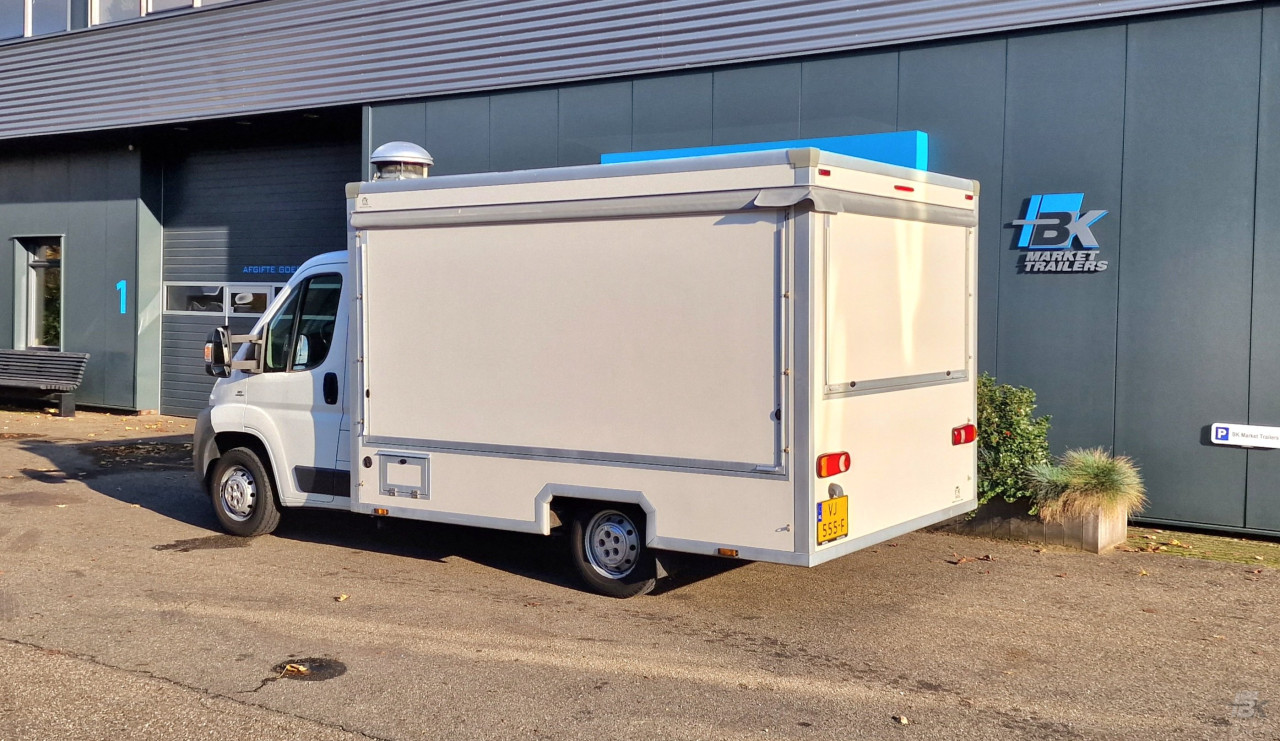 Zijaanzicht van een verkoopwagen voor diverse branches met gesloten luifel
