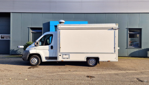 Zijaanzicht van een verkoopwagen voor diverse branches met gesloten luifel